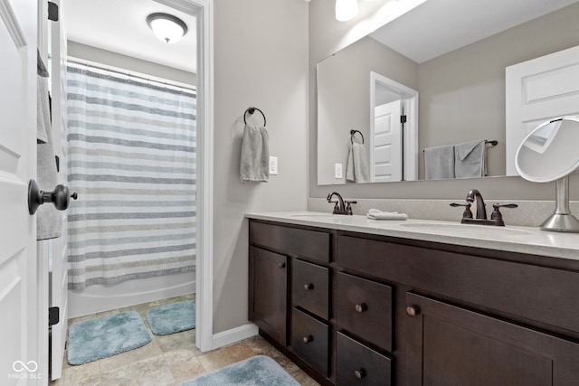 bathroom featuring double vanity, shower / tub combo with curtain, baseboards, and a sink