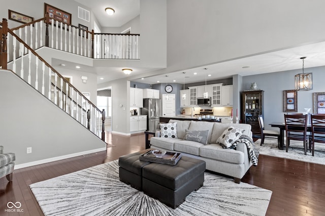 living area featuring stairway, baseboards, visible vents, and dark wood-style flooring