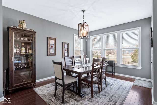 dining area with dark wood finished floors, a notable chandelier, and baseboards