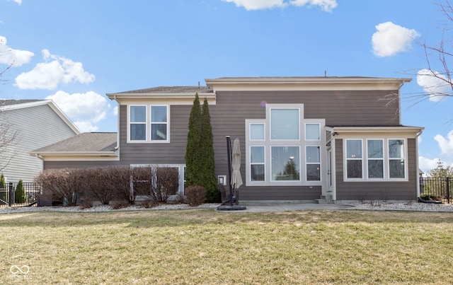 back of property featuring a lawn and fence