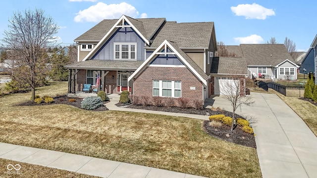 view of front of property featuring a front yard, driveway, a porch, brick siding, and board and batten siding