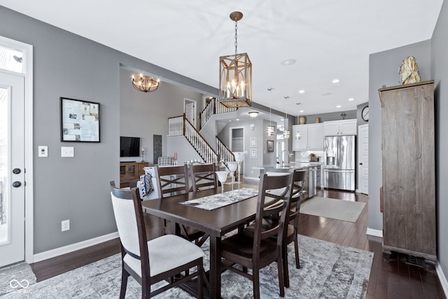 dining area with dark wood finished floors, baseboards, stairs, and an inviting chandelier