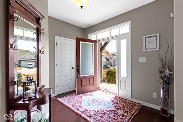 foyer entrance featuring baseboards and dark wood finished floors