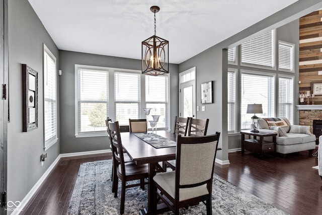 dining space with baseboards, an inviting chandelier, dark wood finished floors, and a fireplace