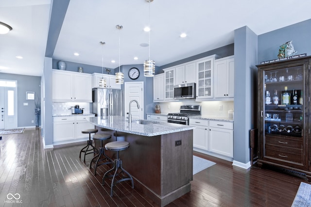 kitchen featuring a sink, a kitchen island with sink, dark wood-style flooring, and stainless steel appliances