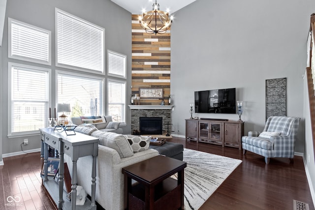 living area with visible vents, a fireplace, dark wood-type flooring, a towering ceiling, and a chandelier