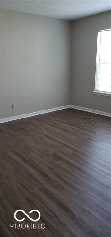 unfurnished room featuring dark wood-style floors and baseboards