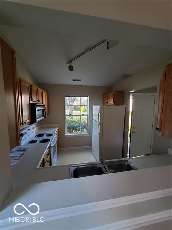 kitchen with brown cabinets, light countertops, visible vents, a sink, and white appliances