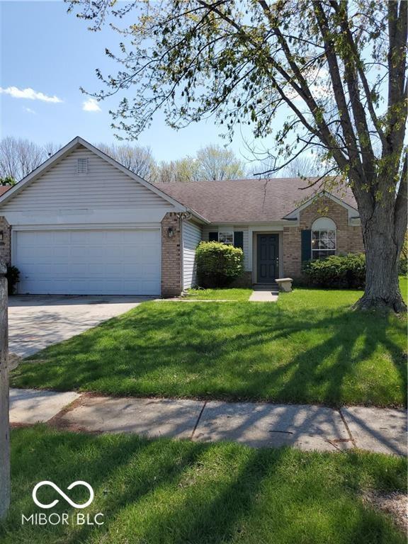 single story home with a garage, driveway, brick siding, and a front lawn