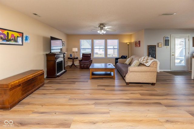 living area with light wood finished floors, visible vents, and a fireplace