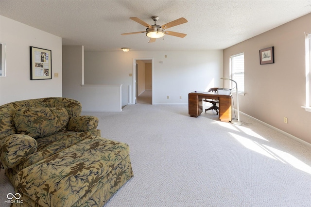 sitting room with light colored carpet, a textured ceiling, baseboards, and a ceiling fan