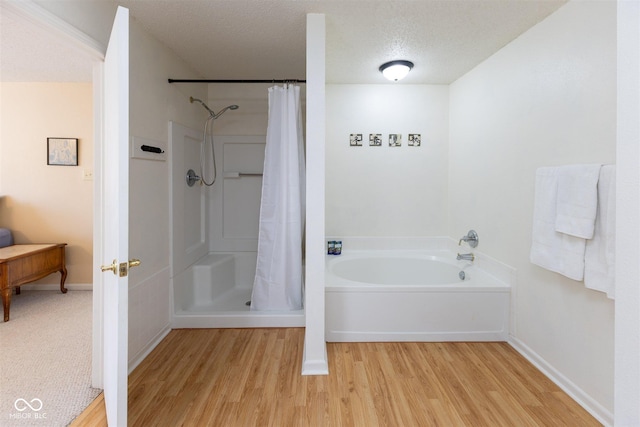 full bath featuring baseboards, a garden tub, a shower with curtain, wood finished floors, and a textured ceiling