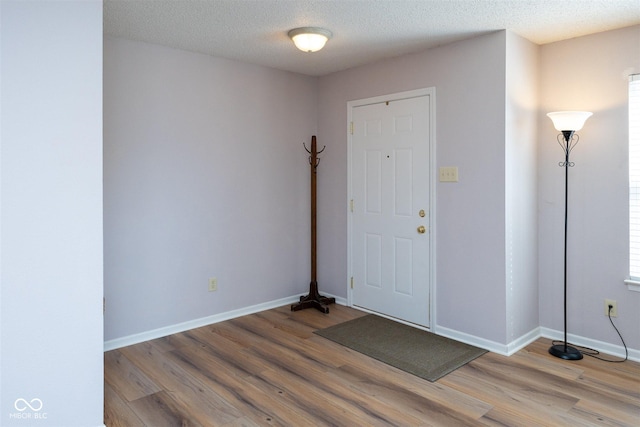 foyer featuring baseboards, a textured ceiling, and light wood-style flooring