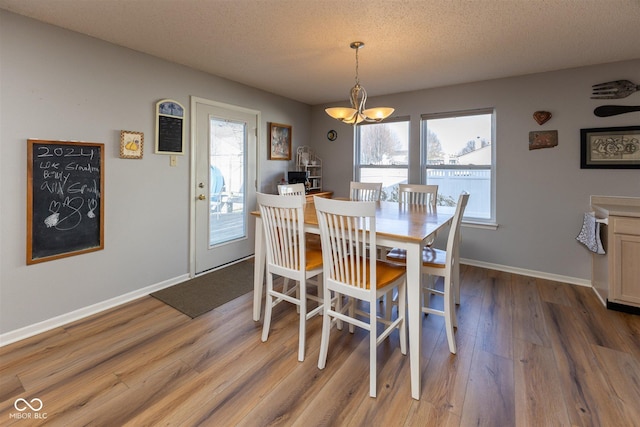 dining room with a chandelier, a textured ceiling, baseboards, and wood finished floors