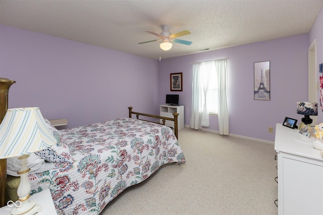 bedroom featuring light carpet, ceiling fan, a textured ceiling, and baseboards