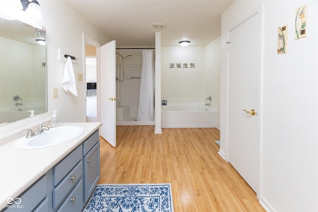 bathroom featuring visible vents, a shower with curtain, a tub to relax in, wood finished floors, and vanity