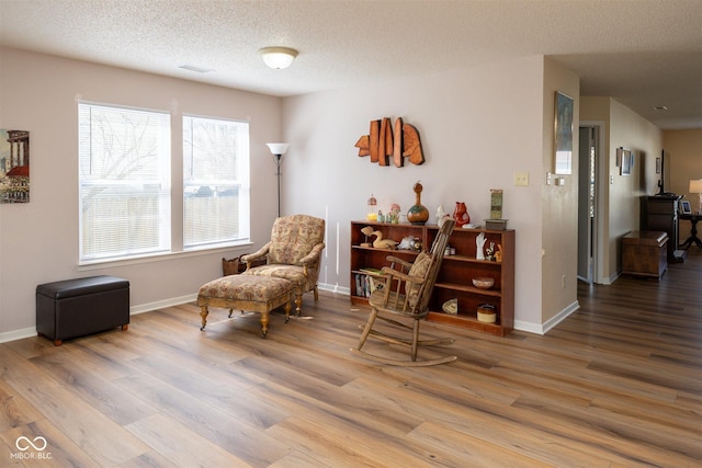 sitting room featuring visible vents, baseboards, a textured ceiling, and wood finished floors