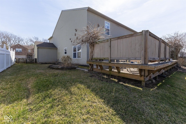 rear view of property featuring a wooden deck, a yard, and fence