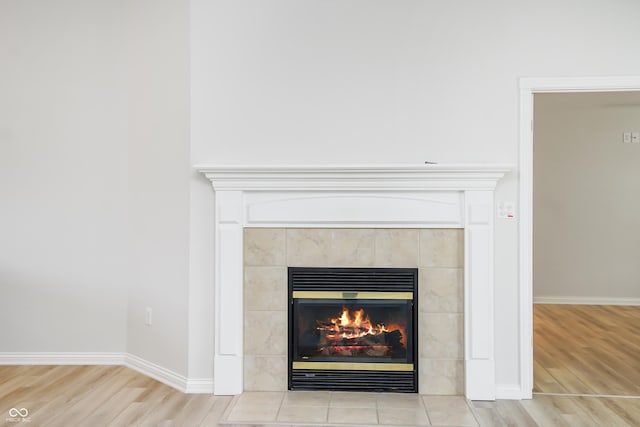 details with a tiled fireplace, baseboards, and wood finished floors