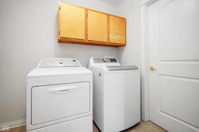 washroom featuring cabinet space, light wood-style floors, and washer and clothes dryer