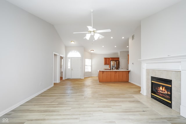 unfurnished living room with a tiled fireplace, visible vents, light wood-type flooring, and baseboards