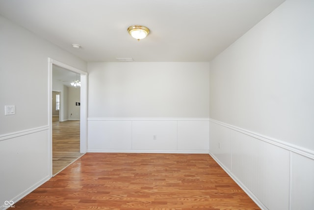 spare room featuring a wainscoted wall and light wood finished floors