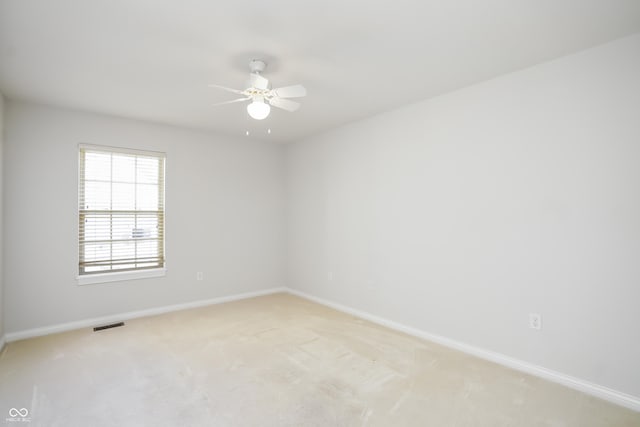 unfurnished room featuring visible vents, baseboards, light colored carpet, and a ceiling fan