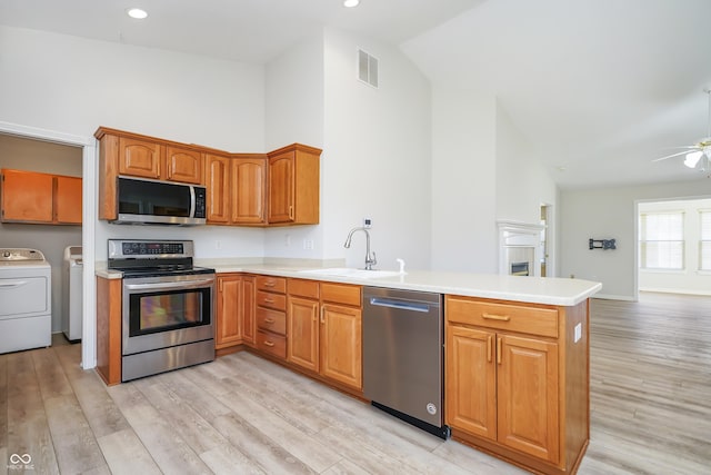 kitchen with visible vents, a peninsula, separate washer and dryer, a sink, and stainless steel appliances