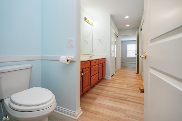 bathroom featuring toilet, wood finished floors, recessed lighting, baseboards, and vanity