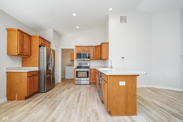 kitchen featuring visible vents, a peninsula, a sink, stainless steel appliances, and light wood-style floors