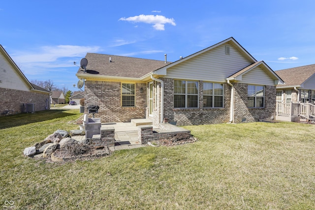 back of house featuring brick siding, central AC unit, a lawn, and a patio area