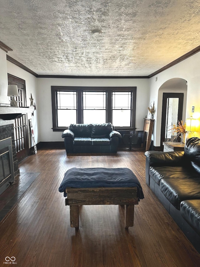 living area featuring arched walkways, a glass covered fireplace, a textured ceiling, and wood-type flooring