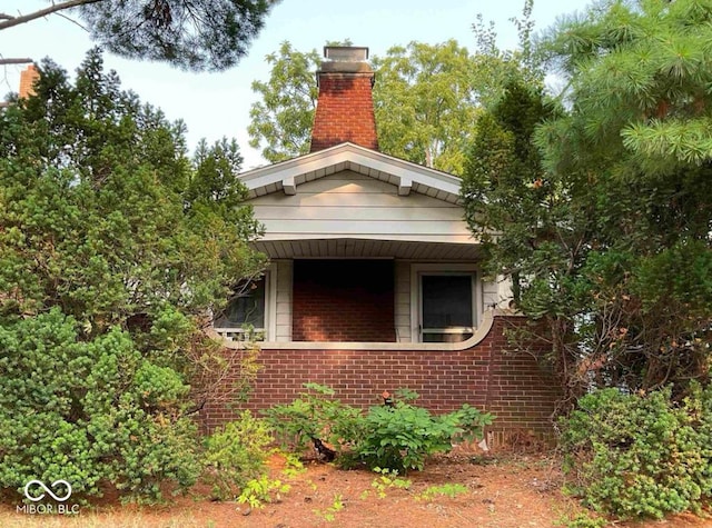 view of property exterior with brick siding and a chimney