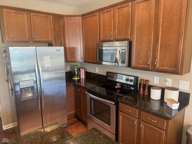 14309 Shooting Star Dr, Noblesville, IN 46060 - kitchen with appliances with stainless steel finishes, wood finished floors, dark stone countertops, and brown cabinets