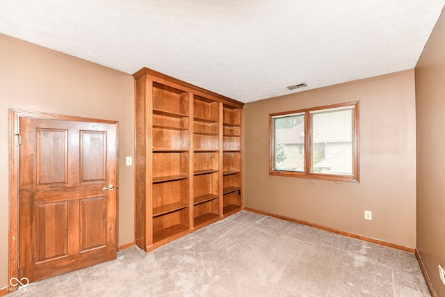 spare room with visible vents, light colored carpet, a textured ceiling, and baseboards