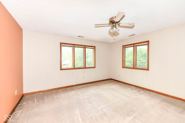 unfurnished room with visible vents, plenty of natural light, light carpet, and baseboards