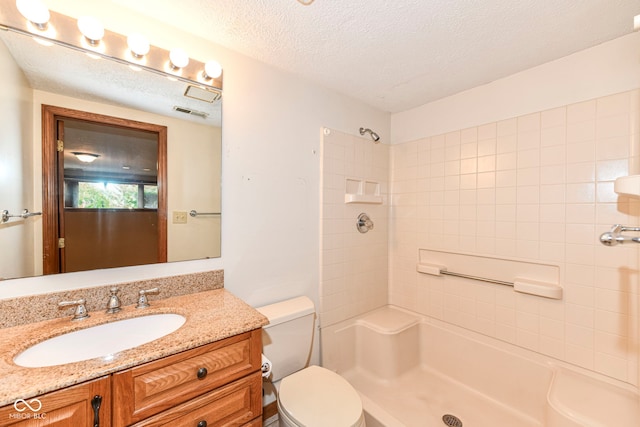 full bathroom featuring a shower, a textured ceiling, toilet, and vanity