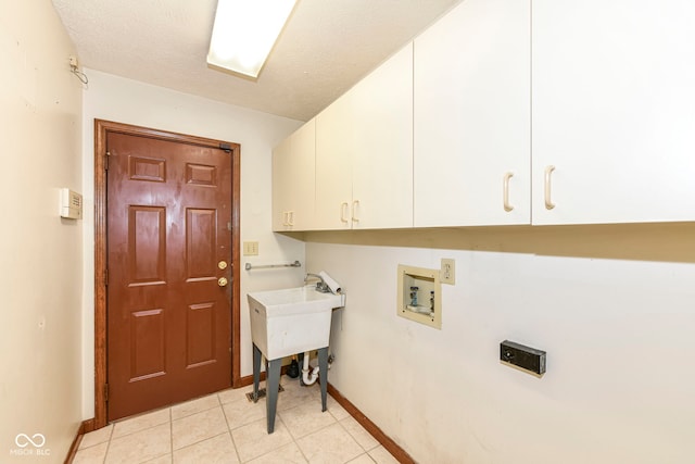 laundry area featuring washer hookup, light tile patterned floors, cabinet space, a textured ceiling, and baseboards