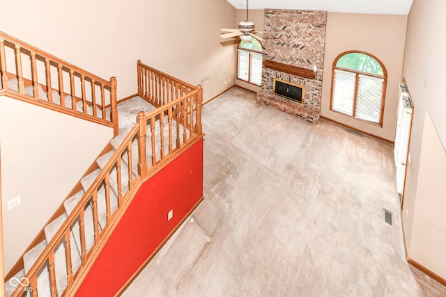 unfurnished living room with carpet, a fireplace, a towering ceiling, ceiling fan, and baseboards