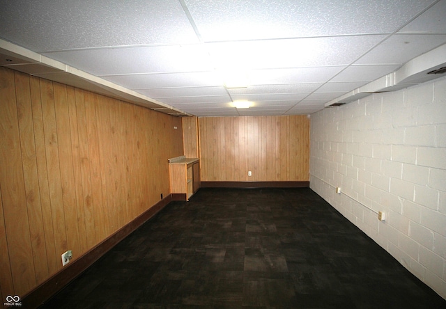 finished basement with wooden walls and a drop ceiling