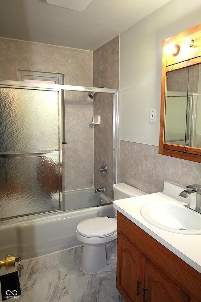 full bath with marble finish floor, enclosed tub / shower combo, vanity, and toilet