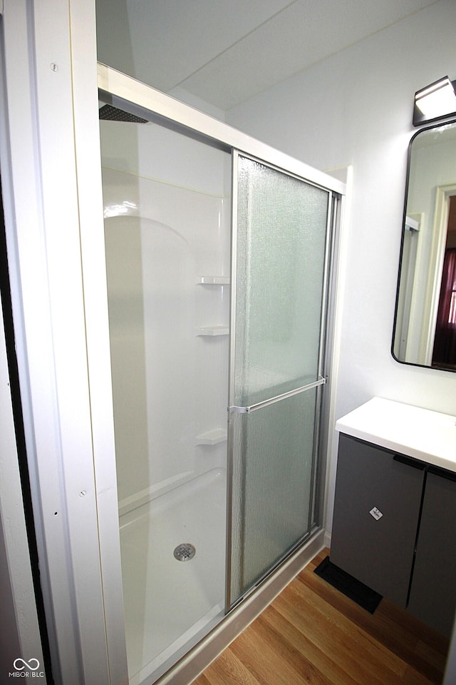 bathroom with a stall shower, wood finished floors, and vanity