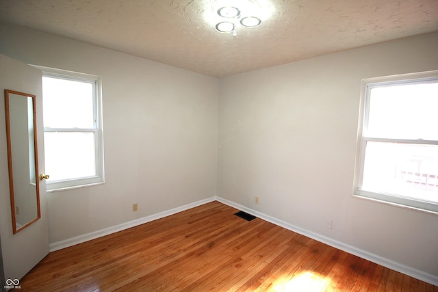 unfurnished room featuring a healthy amount of sunlight, light wood finished floors, and baseboards