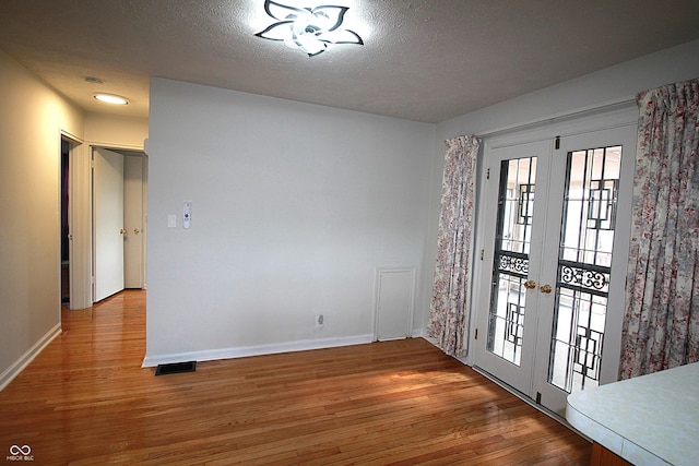 foyer entrance with a textured ceiling, wood finished floors, and french doors