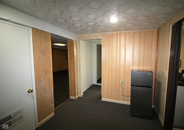 corridor featuring wood walls, baseboards, and visible vents