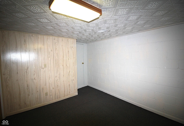 spare room with concrete block wall, an ornate ceiling, and wooden walls