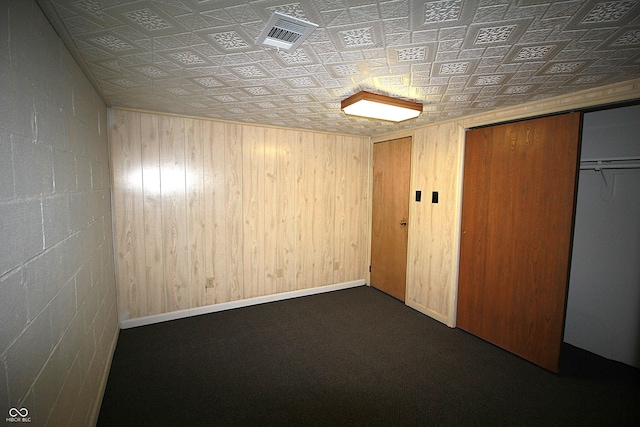 interior space with baseboards, visible vents, and wooden walls