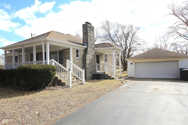 view of front facade featuring a shingled roof, a chimney, a porch, and an outbuilding