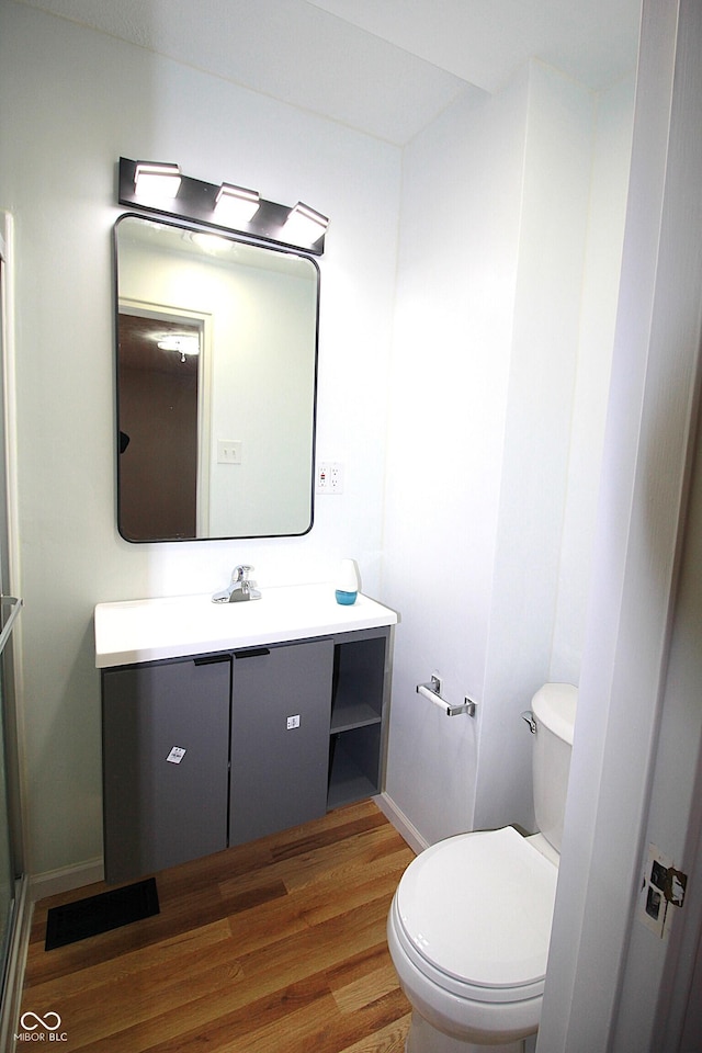 bathroom featuring toilet, wood finished floors, vanity, and baseboards