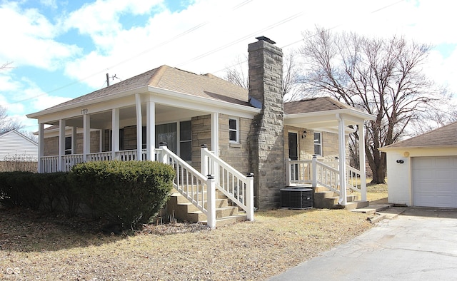 view of front of property featuring a chimney, a porch, a shingled roof, a garage, and cooling unit